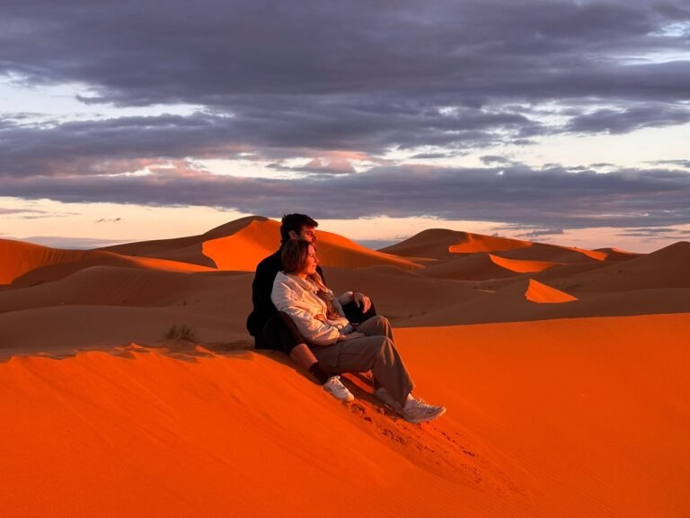 Andrea y Chris sentados en una duna roja al atardecer