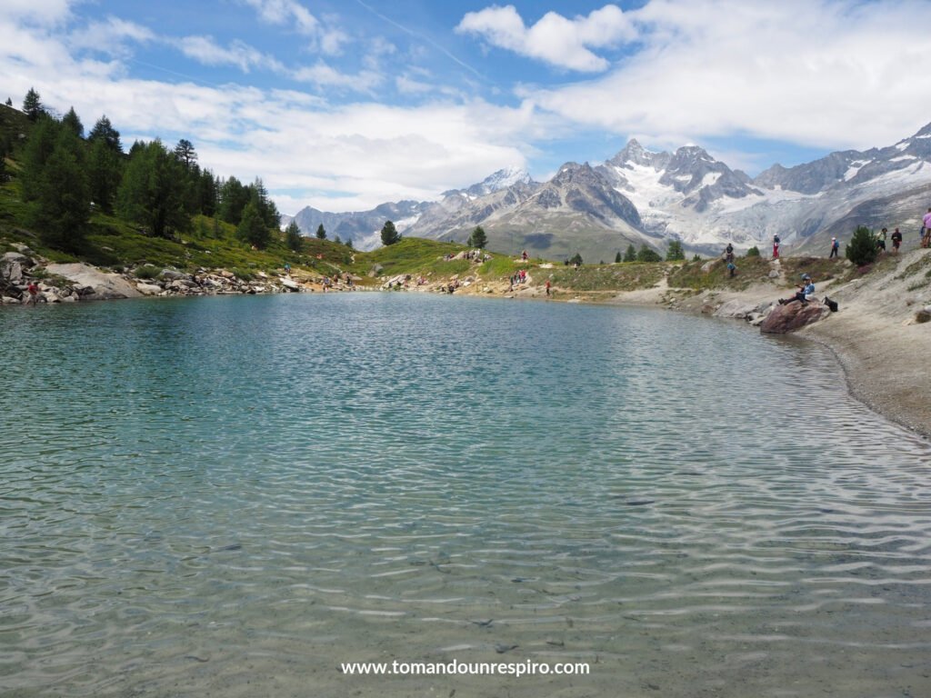 Lago alpino turquesa con montañas nevadas al fondo