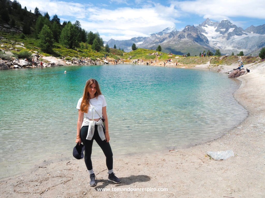 Andrea en la orilla de un lago alpino turquesa